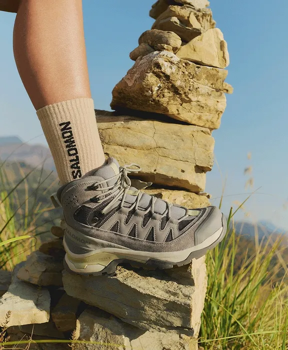 Nahaufnahme eines Salomon Wanderschuhs und einer Socke auf einem Steinhaufen in der Natur.